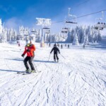 Skiers skiing in a mountain resort with a ski lift in the background