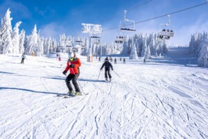 Skiers skiing in a mountain resort with a ski lift in the background